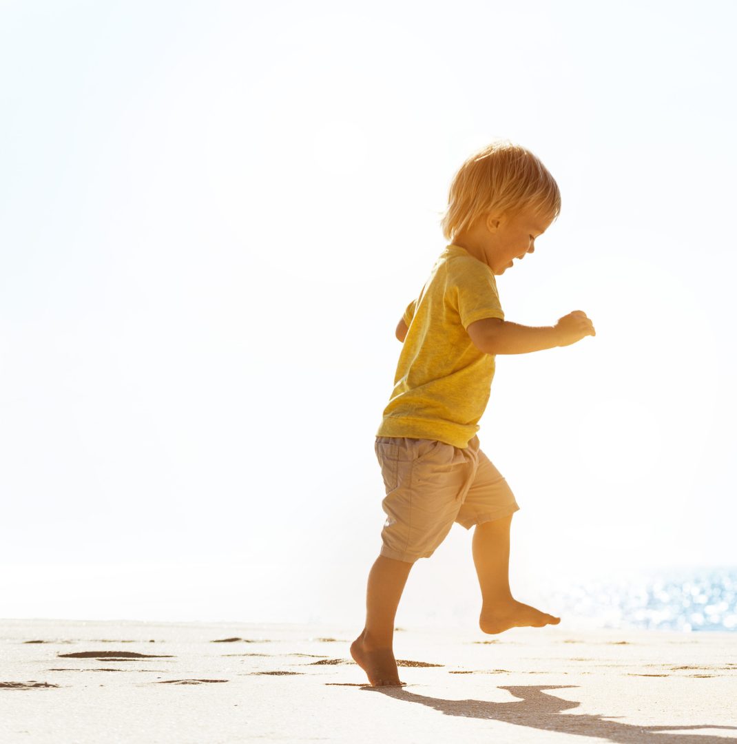 A toddler running along the beach