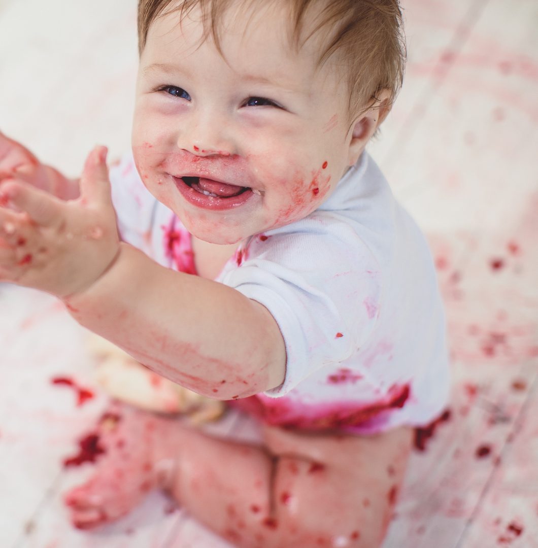 A smiling baby with berry-stained hands