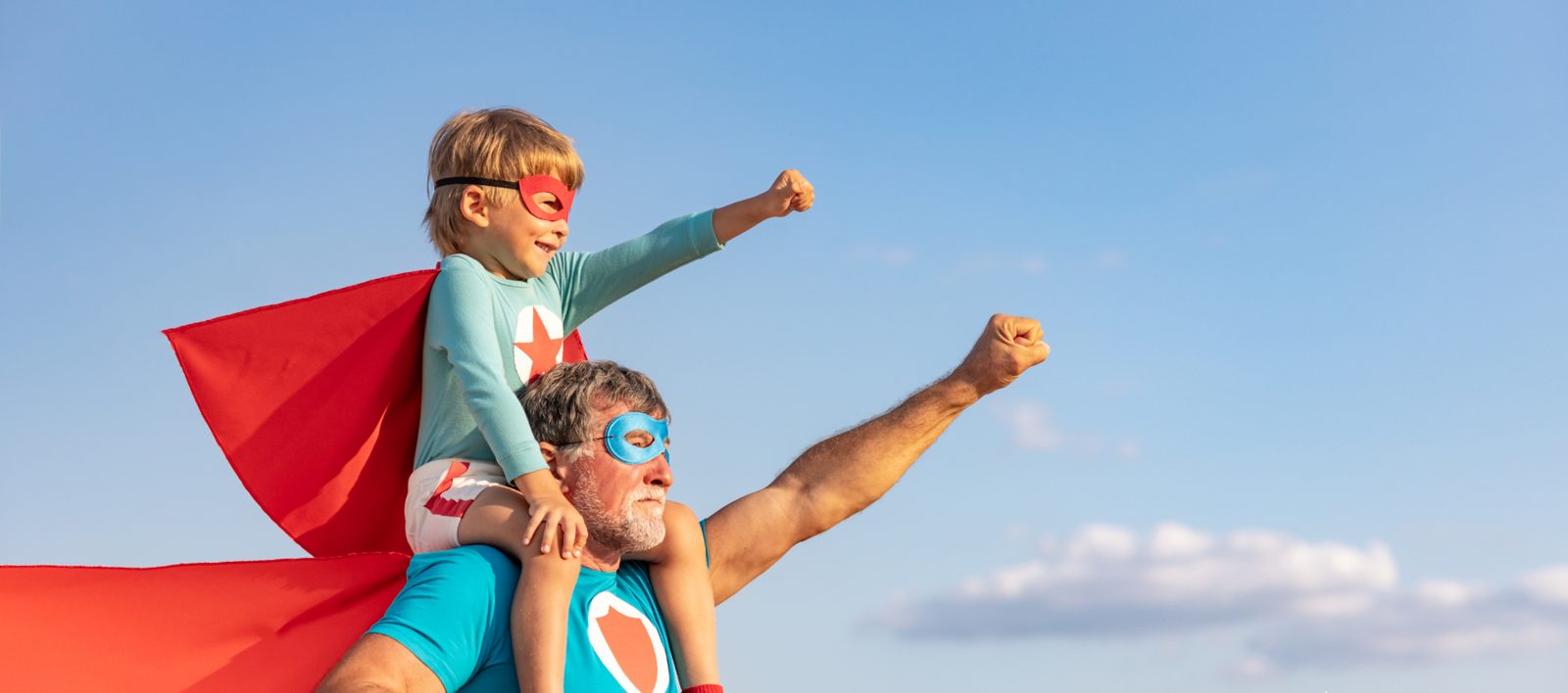 A grandfather and grandchild in superhero capes