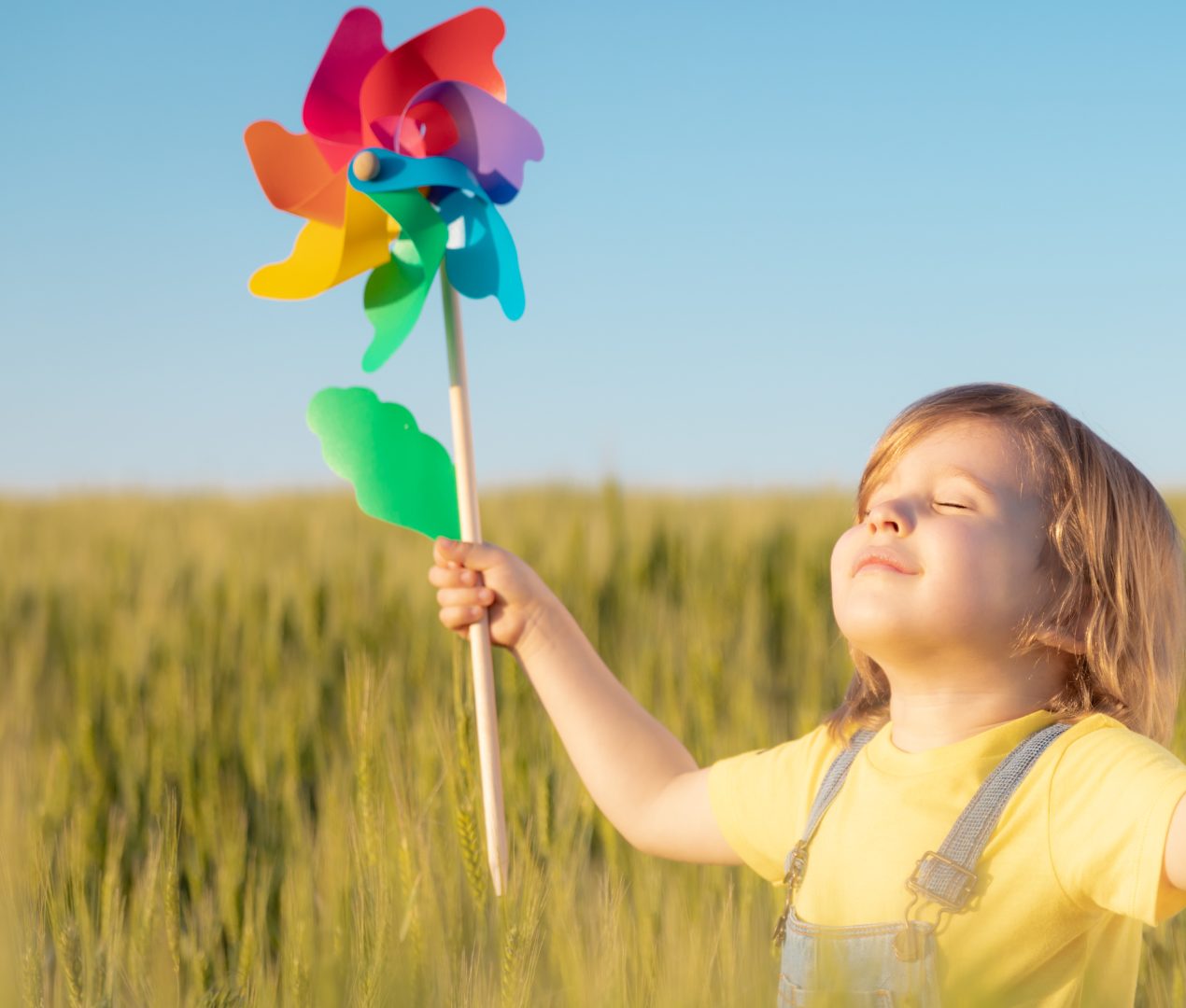 A toddler holding a pinwheel in a wheat field
